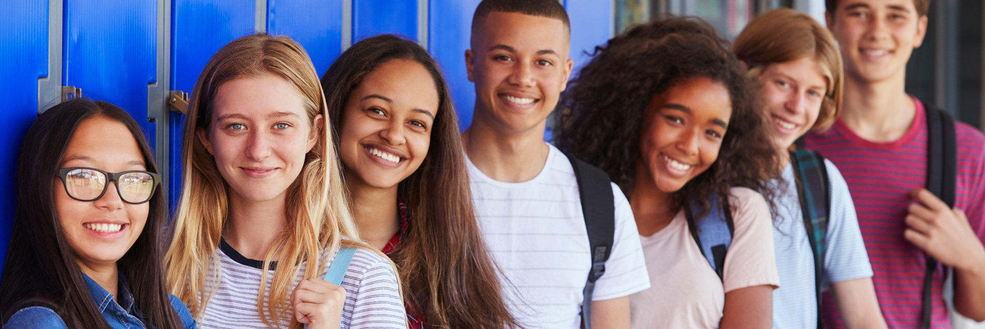 Teenage school kids smiling to camera in school corridor