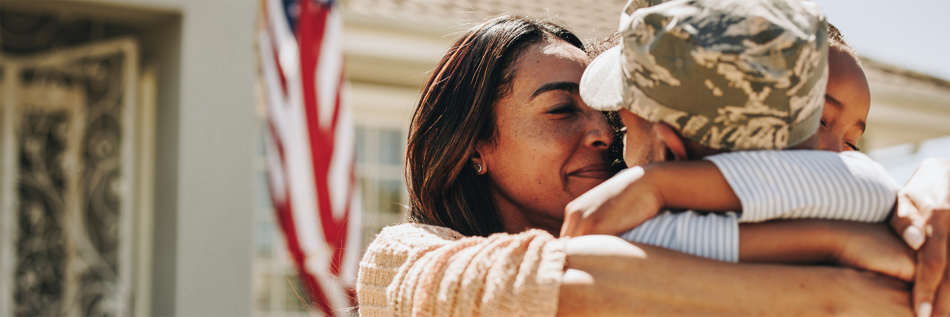 Family hugging their family member who is wearing a military uniform.