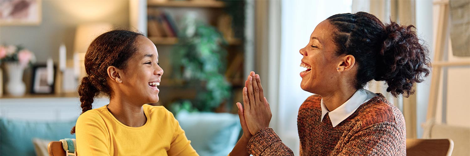 Mom and daughter laughing and high fiving.