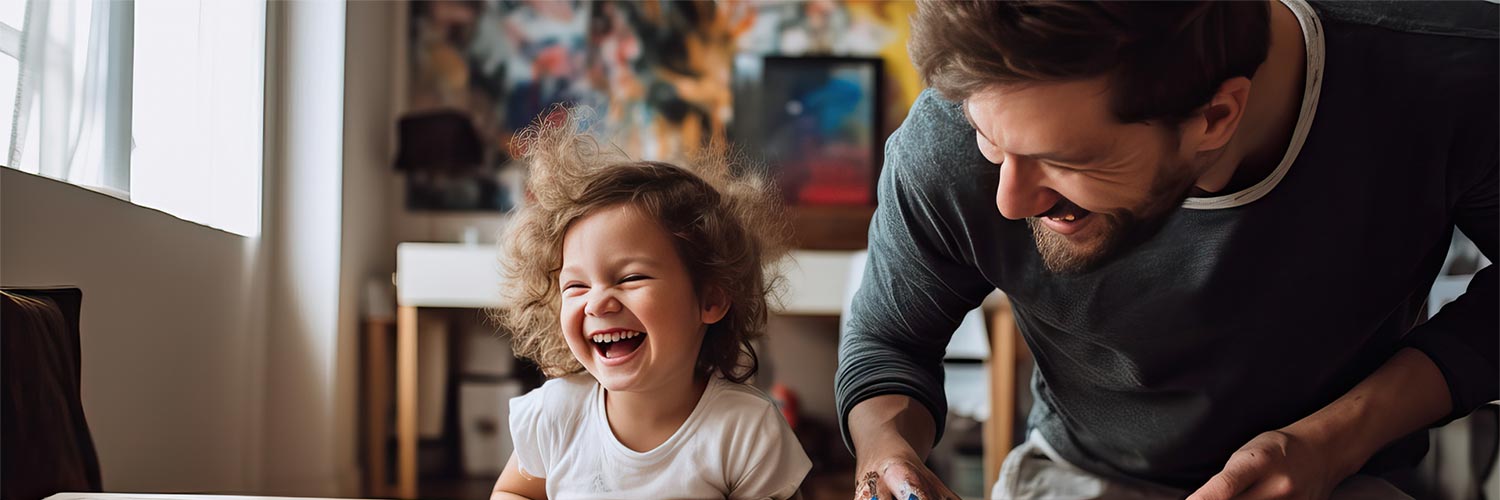 Dad and daughter laughing while panting at a table