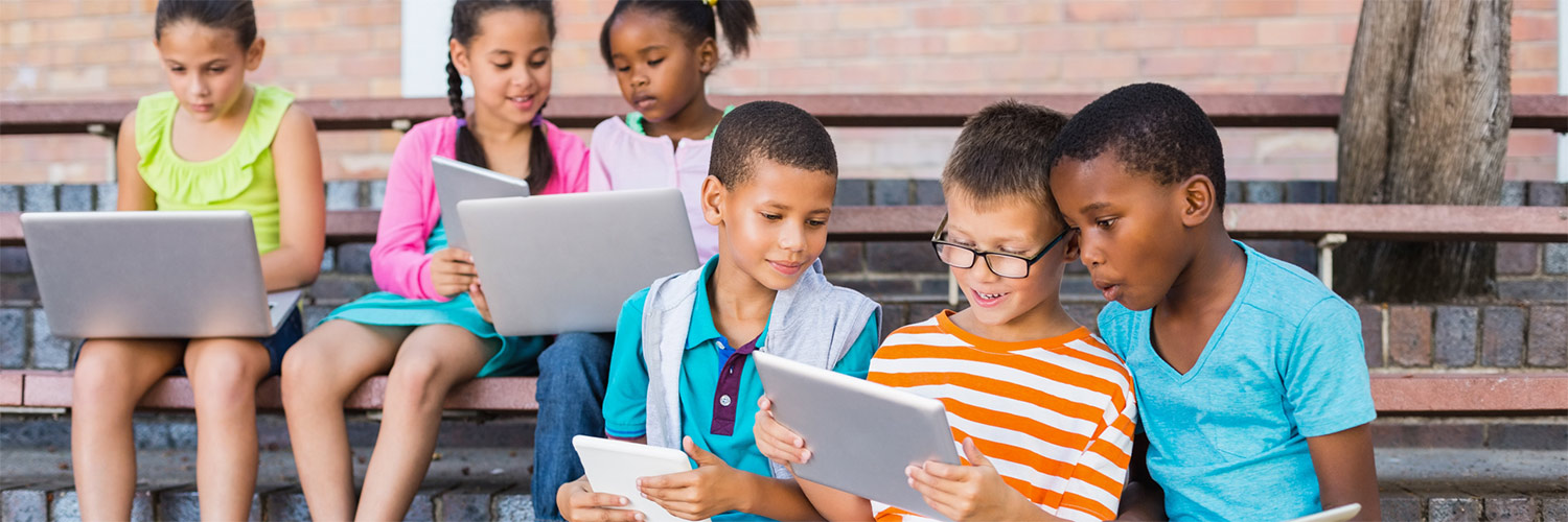 Group of kids sitting on bleachers looking at tablets.