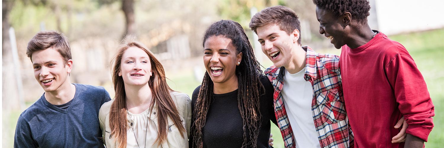 Group of teens standing outside with their arms around each other.