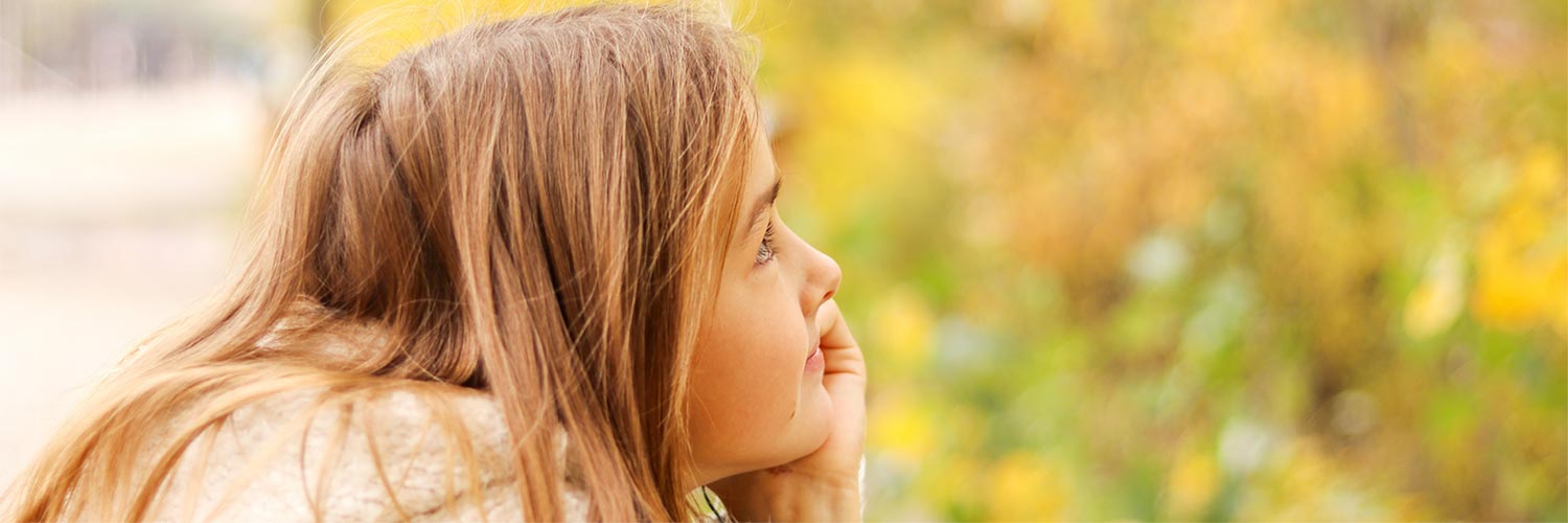 Blonde girl sitting outside looking hopeful