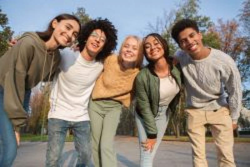 Group of teens standing with their arms over each other's shoulders and smiling.